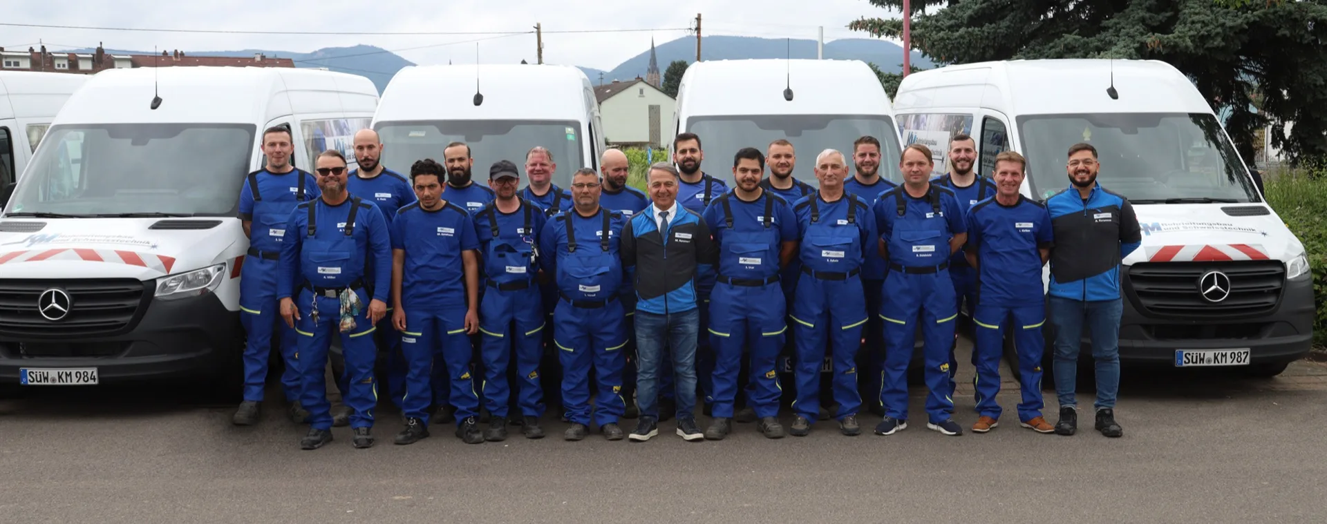 Das Team der KM Rohrleitungsbau und Schweisstechnik GmbH vor den Werkstattfahrzeugen in Edenkoben